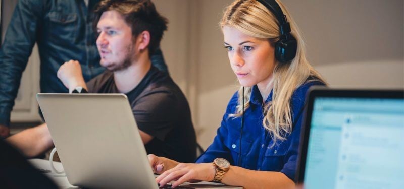 Softwareontwikkelaars werken samen achter laptops in een ontwikkelomgeving