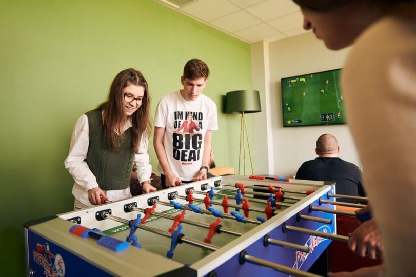 Collega’s spelen tafelvoetbal in een ontspanningsruimte op de NetRom Campus.
