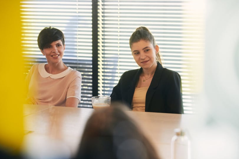 Twee NetRom-collega’s tijdens een gesprek aan tafel op kantoor.