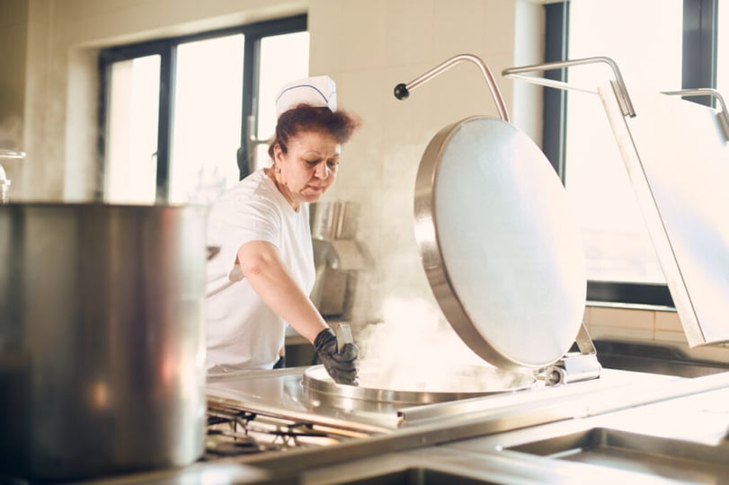 Medewerker bereidt eten in de keuken van het bedrijfsrestaurant op de NetRom Campus.