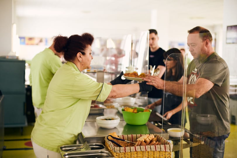 Medewerker ontvangt een warme maaltijd in het bedrijfsrestaurant op de NetRom Campus.