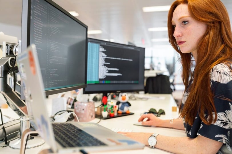 Gefocuste blik van een vrouwelijke software engineer achter haar beeldscherm, werkend aan de architectuur voor het internationaal schalen van een SaaS-platform