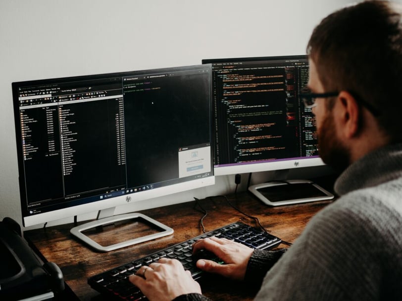 Softwareontwikkelaar werkt met code op meerdere beeldschermen
