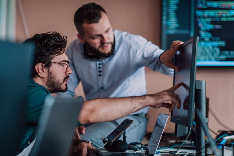 Two software developers collaborating across multiple screens