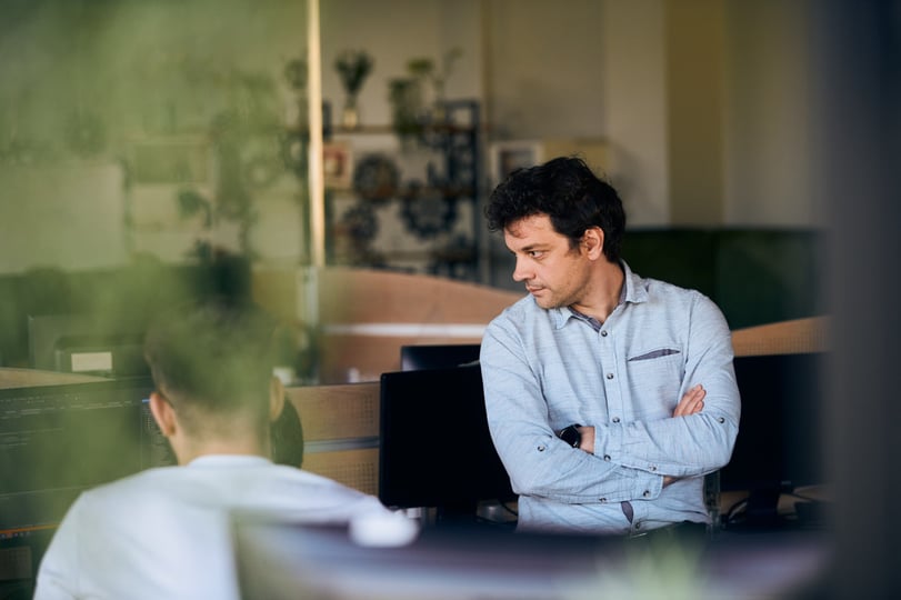 NetRom-collega bespreekt werk met een collega achter een beeldscherm op kantoor.