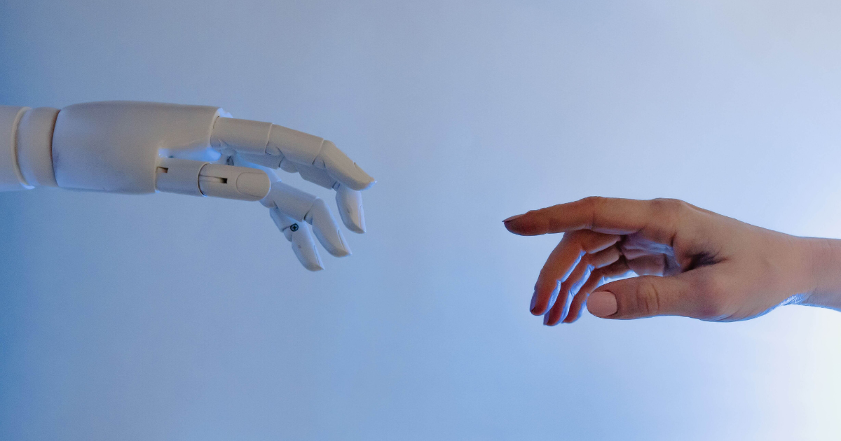 Menselijke hand en robothand die naar elkaar reiken als symbool voor samenwerking tussen mens en AI