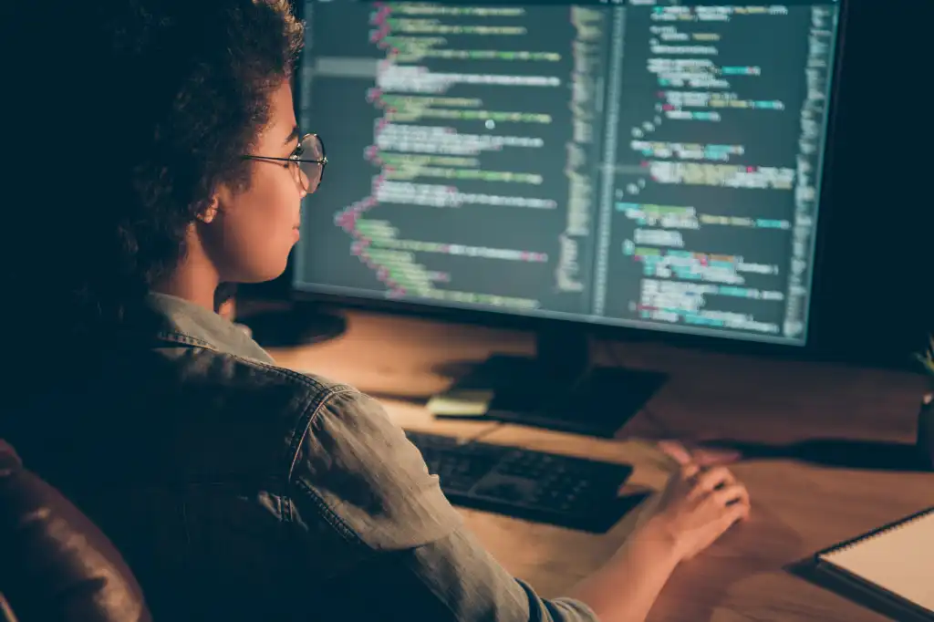 Vrouwelijke softwareontwikkelaar werkt geconcentreerd aan code op een laptop