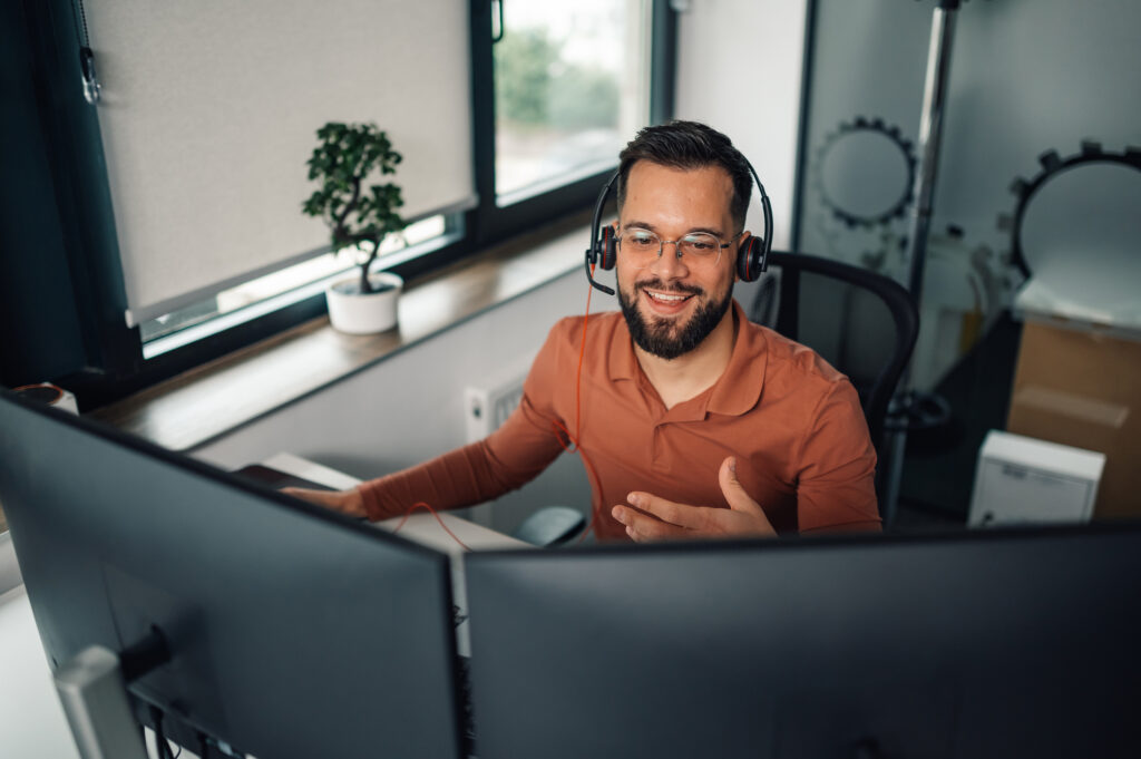 Software developer wearing a headset behind multiple monitors
