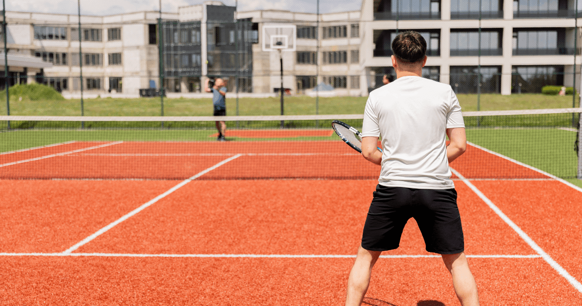 Medewerkers spelen tennis op de sportfaciliteiten van de NetRom Campus in Craiova, ter illustratie van medewerkerstevredenheid en vitaliteit in softwareontwikkeling.