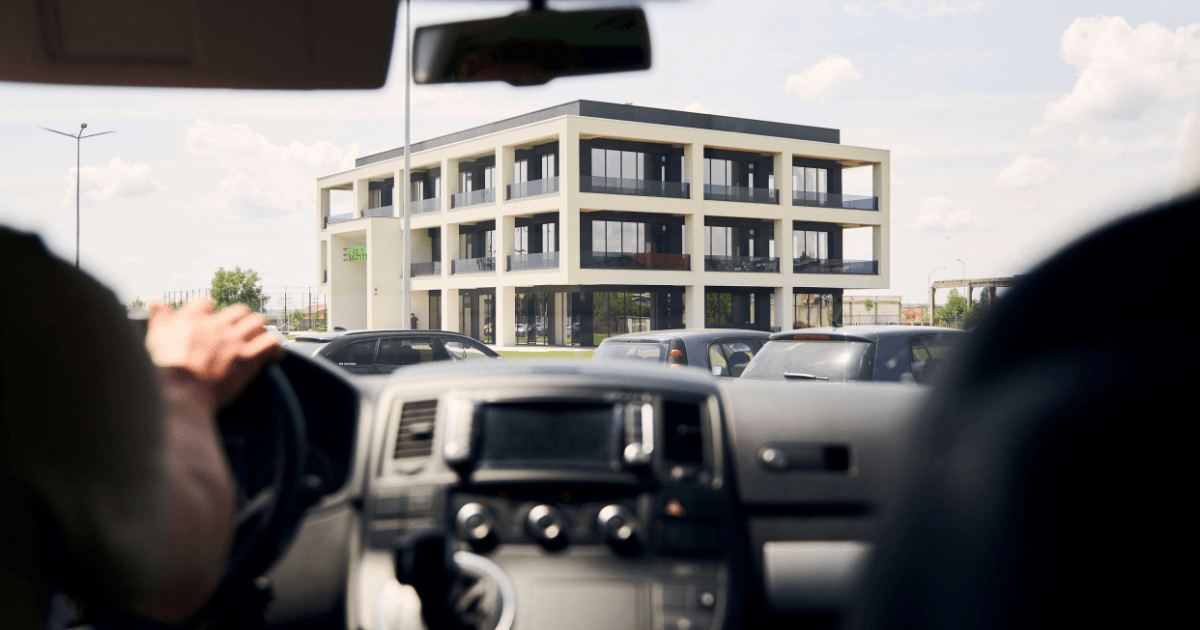 Uitzicht vanuit een auto die aanrijdt bij het moderne kantoorgebouw van de NetRom Software campus in Craiova, gebruikt als visualisatie van een klantbezoek op locatie.