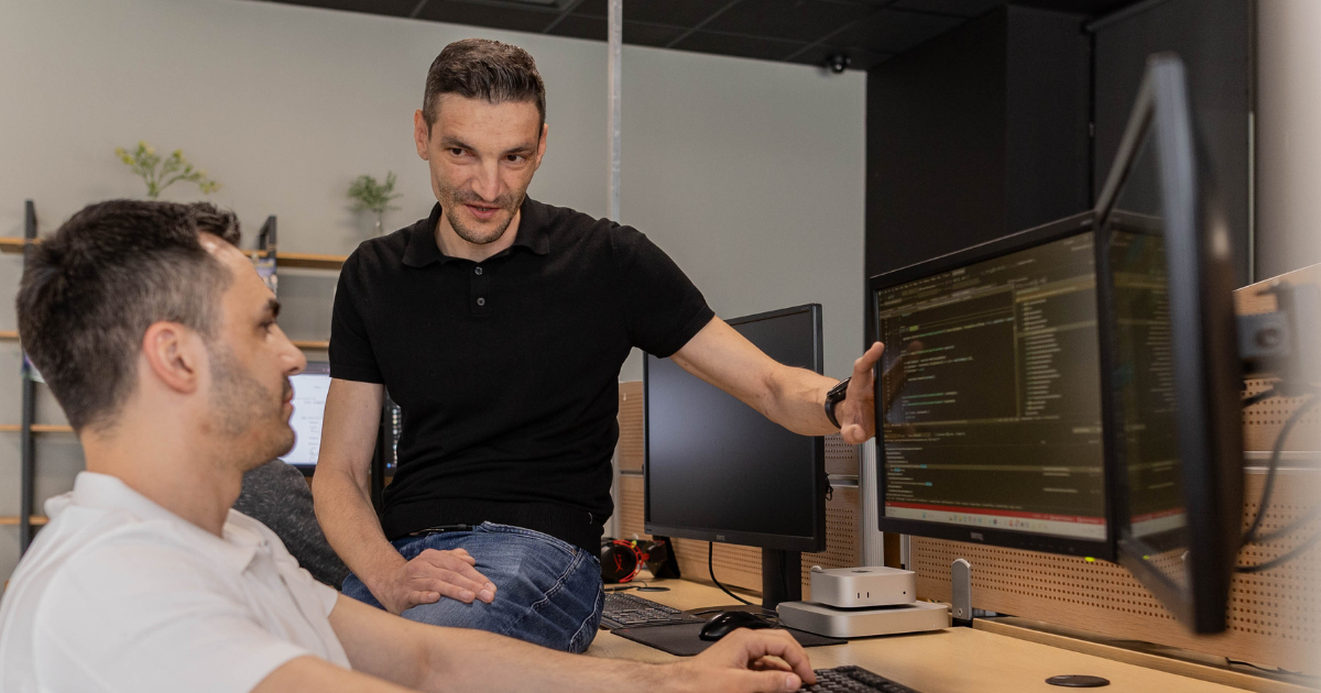Two software developers are discussing code on a computer screen