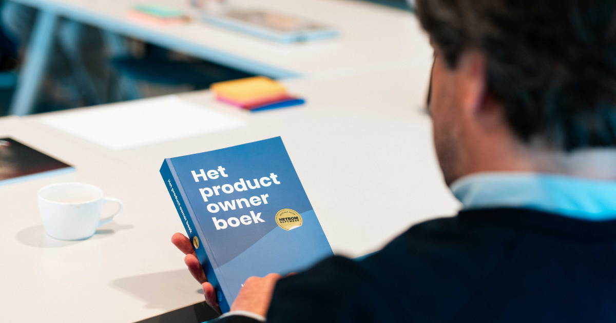 Deelnemer houdt Het product owner boek vast tijdens een NetRom-sessie.