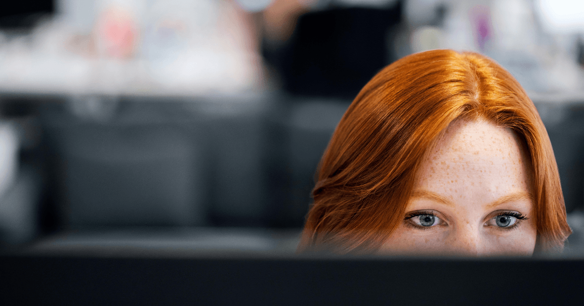 Gefocuste blik van een vrouwelijke software engineer achter haar beeldscherm, werkend aan de architectuur voor het internationaal schalen van een SaaS-platform